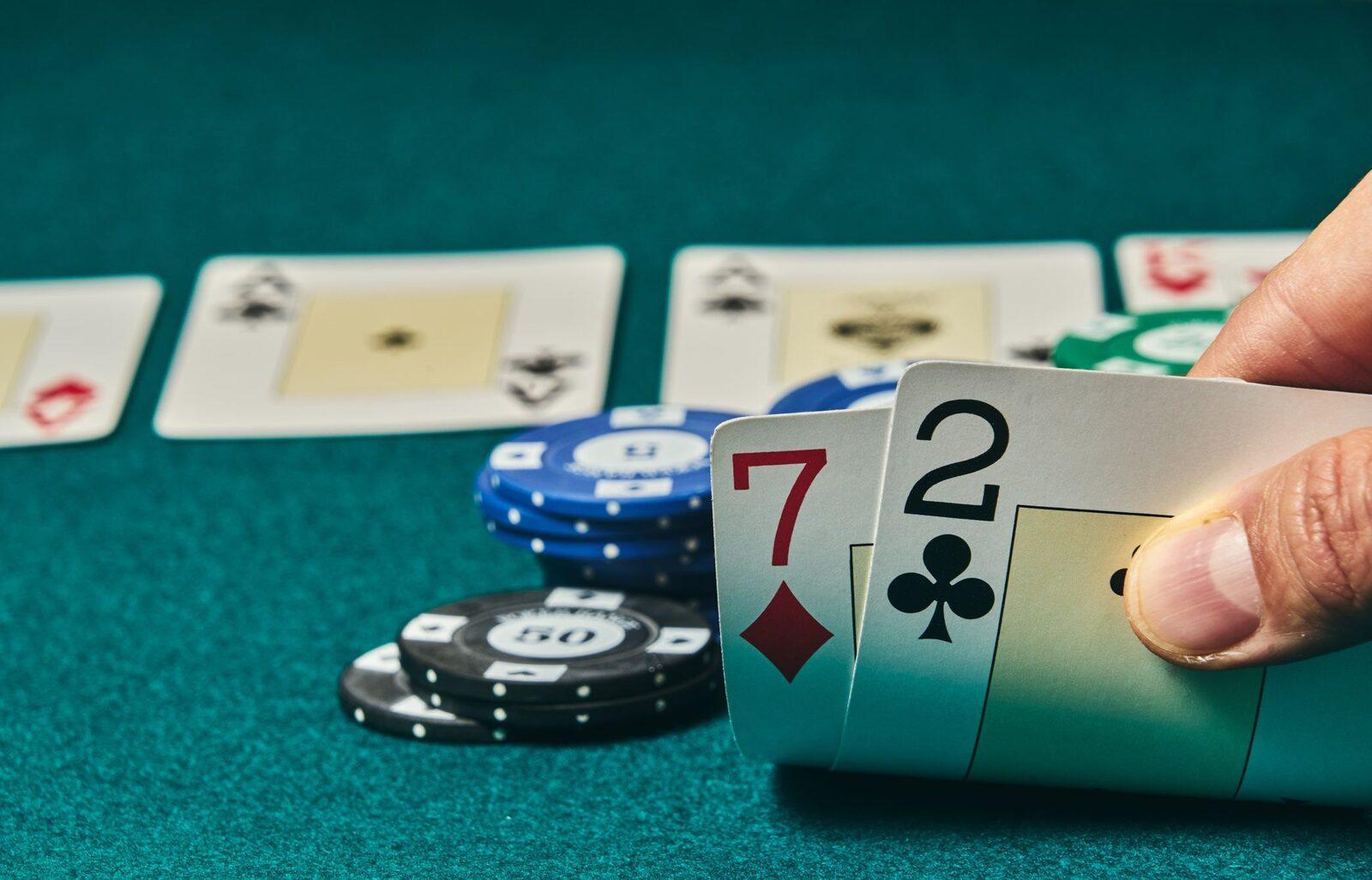 A player holding seven-two offsuit, poker's worst starting hand, over a green felt table