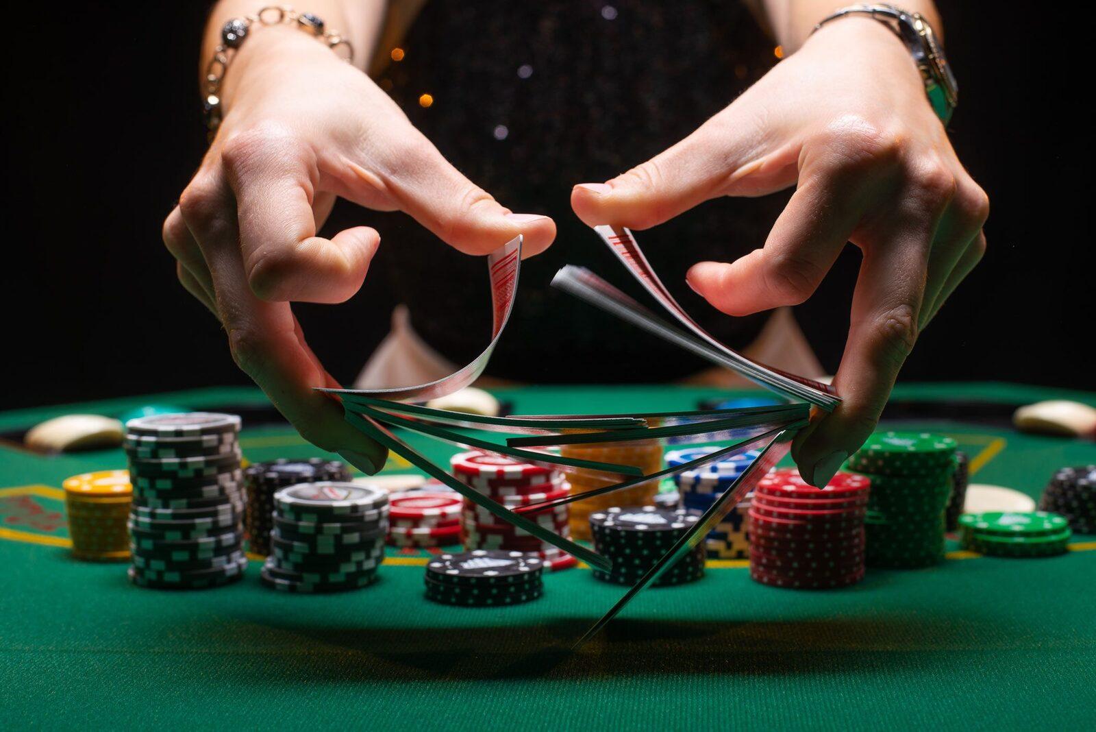 Hands riffle-shuffling a deck of cards over stacks of poker chips