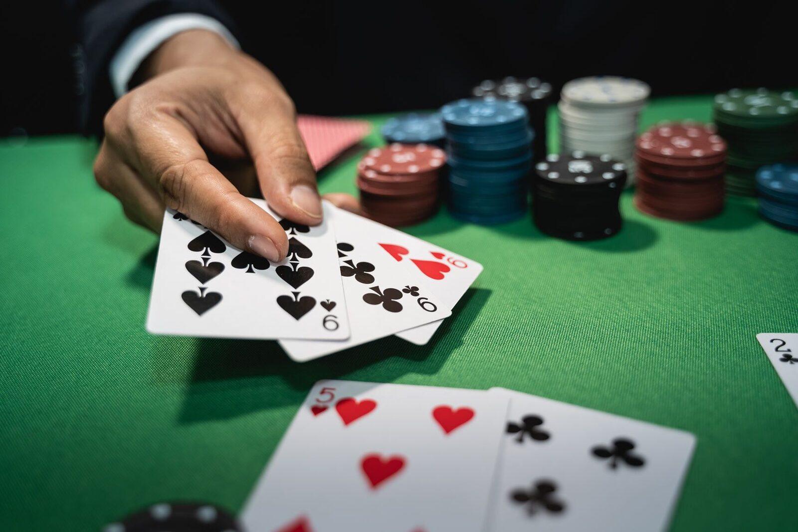 A poker player in a suit holding two cards over stacks of chips