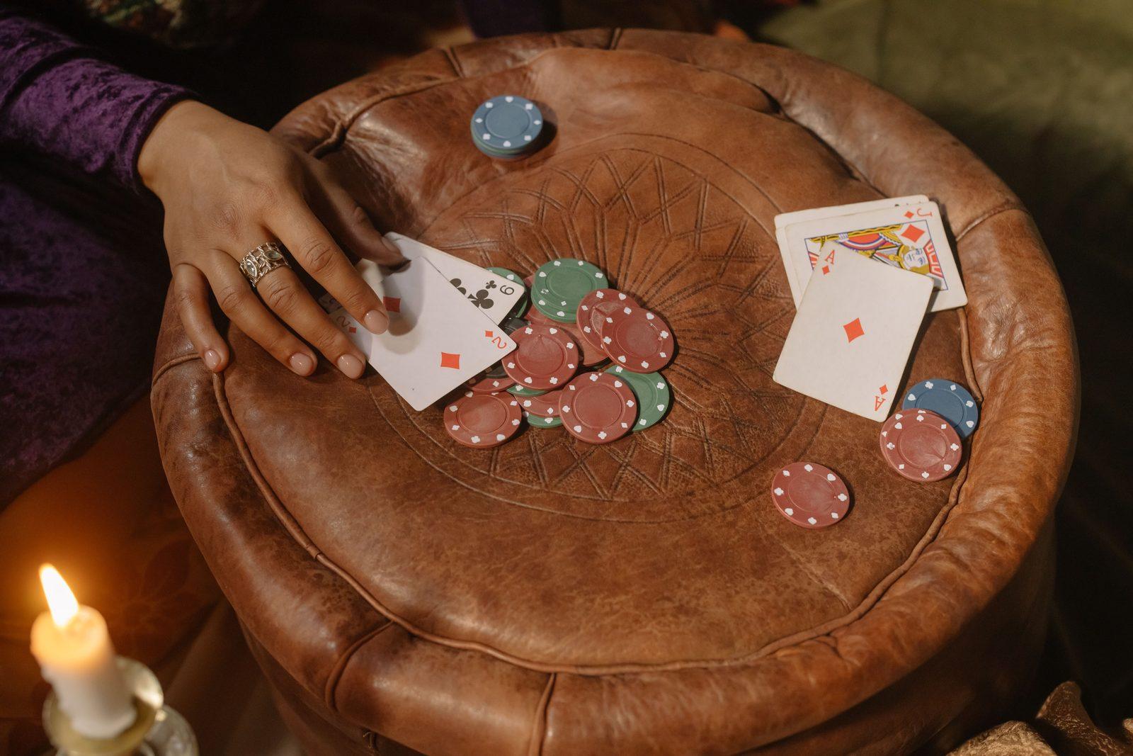 Several players' hands mid-game around a poker table, cards and chips in play