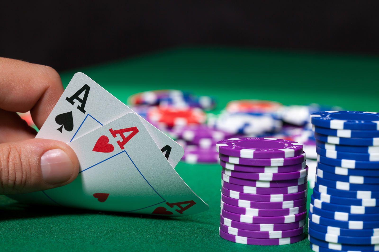 Two ace cards beside purple and blue poker chip stacks on green felt
